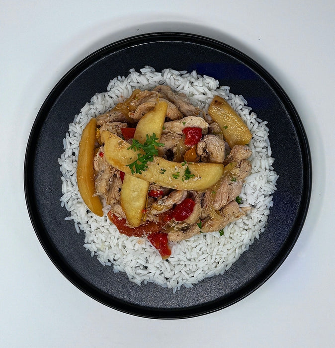 Dish of chicken with vegetables over rice on a black plate