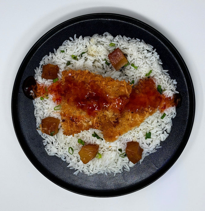 Plated dish with rice, fried chicken, and sauce on a white background
