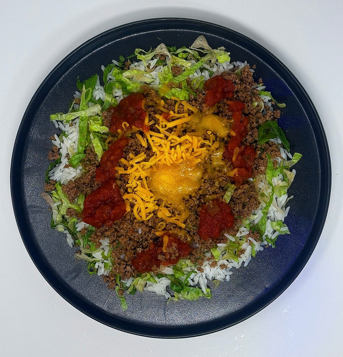 Plated dish with ground meat, lettuce, cheese, and salsa on a white background