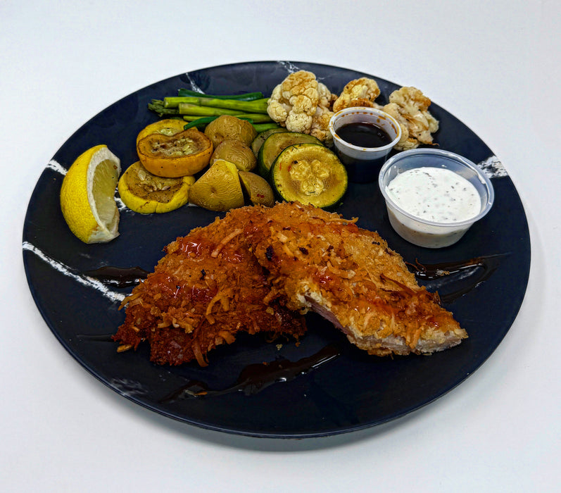 Plated dish with fried fish, vegetables, and sauces on a black plate.