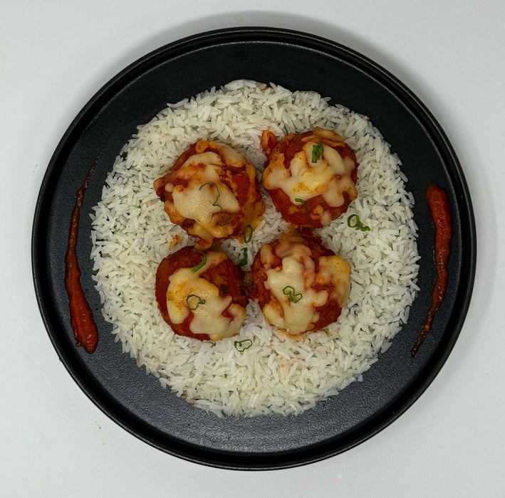 Plated dish with seafood on rice, garnished with green onions, on a white background