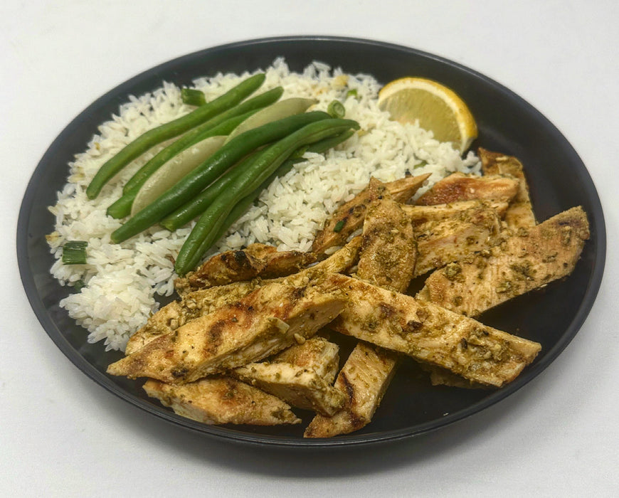 PestoChicken-SpartanMealPreps-NJMealPrepDelivery - pesto chicken strips paired with jasmine rice, green beans and lemon on a black plate.
