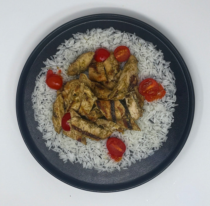 Plated dish with rice, grilled chicken, and cherry tomatoes on a white background