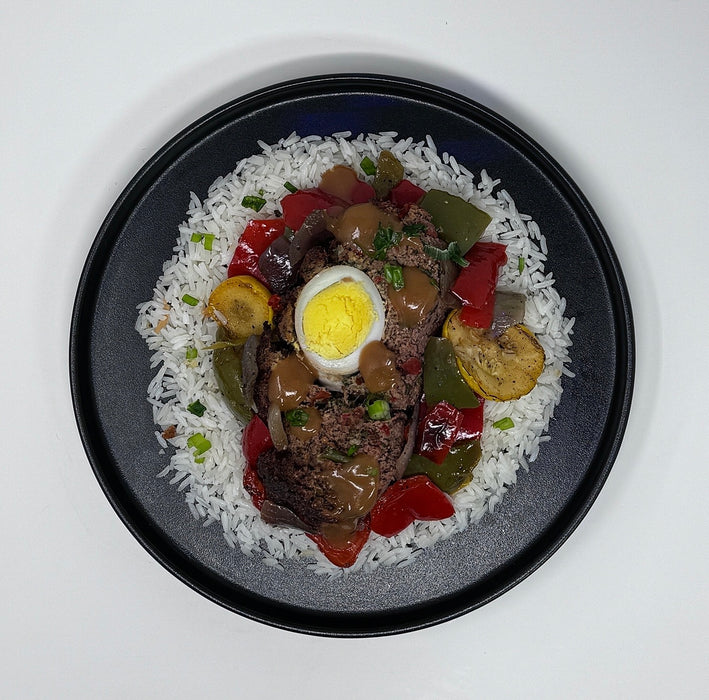 Plated dish with meat, vegetables, and a hard-boiled egg on a bed of rice.
