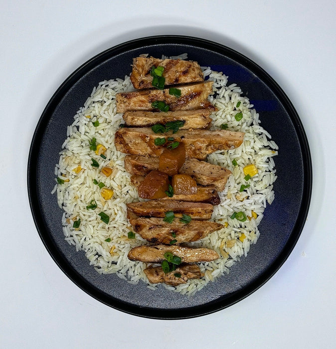 Plated dish of rice with grilled chicken and garnishes on a white background