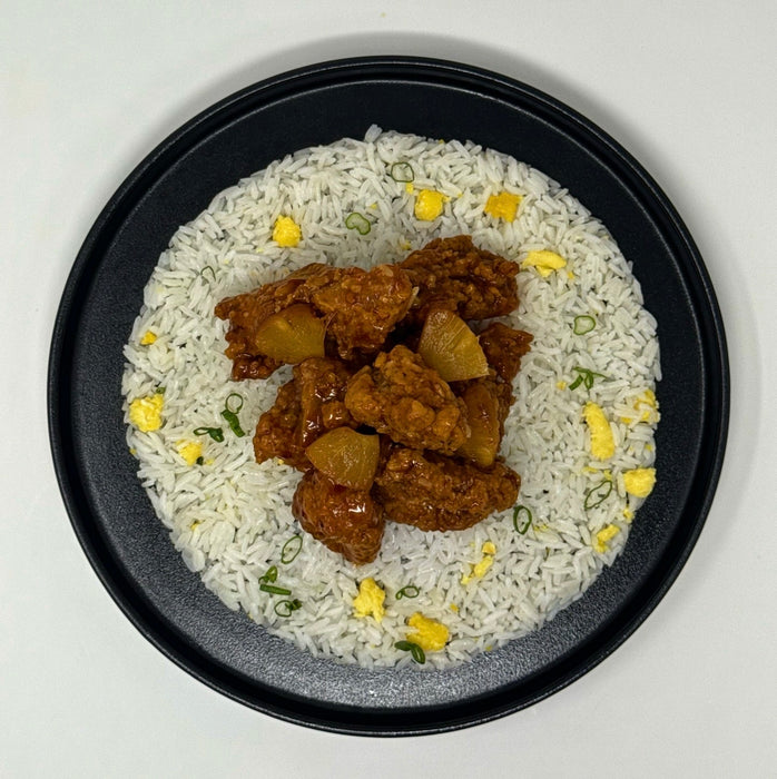 Plated dish of rice with chicken and pineapple pieces on a white background
