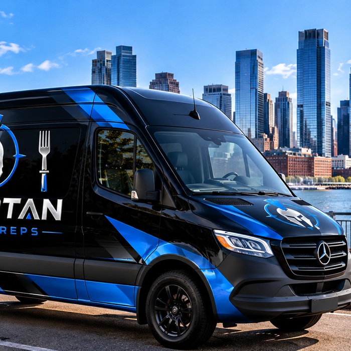 Spartan Meal Preps branded delivery van featuring the blue Spartan logo along the Jersey City, NJ waterfront, representing healthy meal prep delivery and high-protein prepared meals in Jersey City, New Jersey.