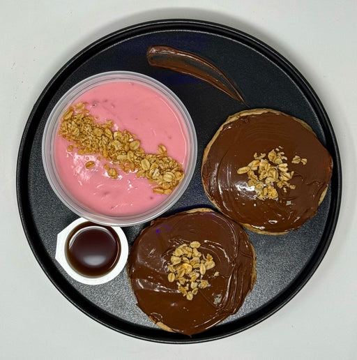 Two chocolate-dipped cookies with a pink dessert and chocolate sauce on a black plate.