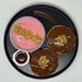 Two chocolate-dipped cookies with a pink dessert and chocolate sauce on a black plate.