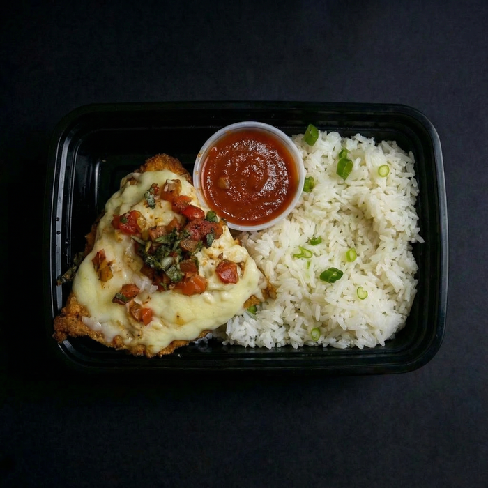 Plated meal with chicken dish, rice, and sauce on a dark background