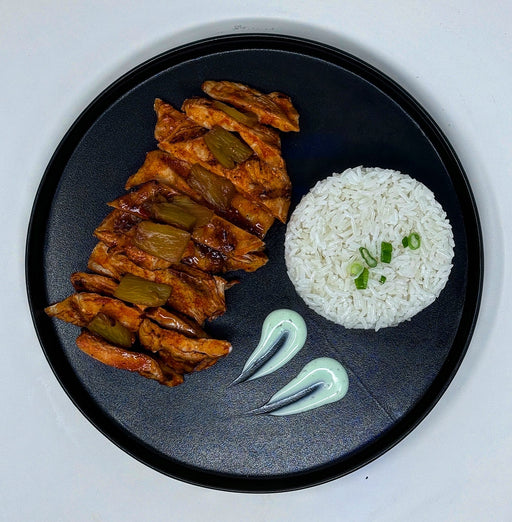 buffalo chicken breast cut into slices paired with pineapple bites and a side of jasmine rice and sauce.