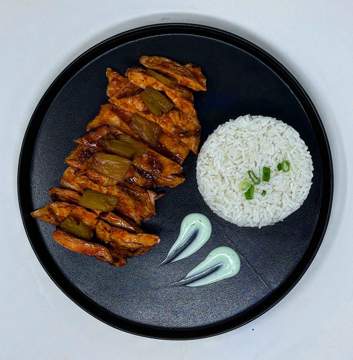 buffalo chicken breast cut into slices paired with pineapple bites and a side of jasmine rice and sauce.