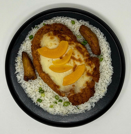Plated dish with fried chicken, rice, and vegetables on a white background