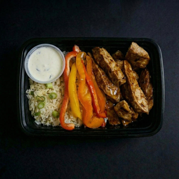 Plated meal with rice, vegetables, and meat on a dark background
