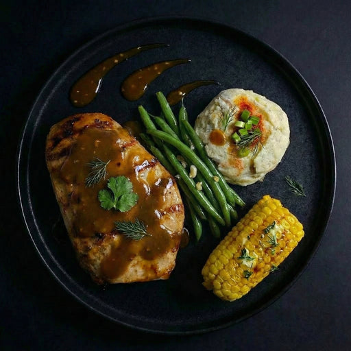 Plated meal with meat, green beans, and corn on a dark background