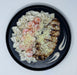 Plated dish with grilled chicken, shrimp, and pasta on a black plate.