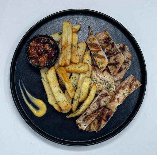 Plated dish with fries, grilled meat, and a side of sauce on a gray background