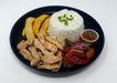 Plated meal with rice, fried chicken, vegetables, and a side of sauce on a white background
