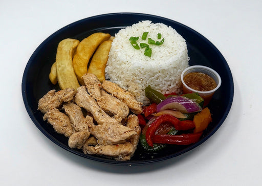 Plated meal with rice, fried chicken, vegetables, and a side of sauce on a white background