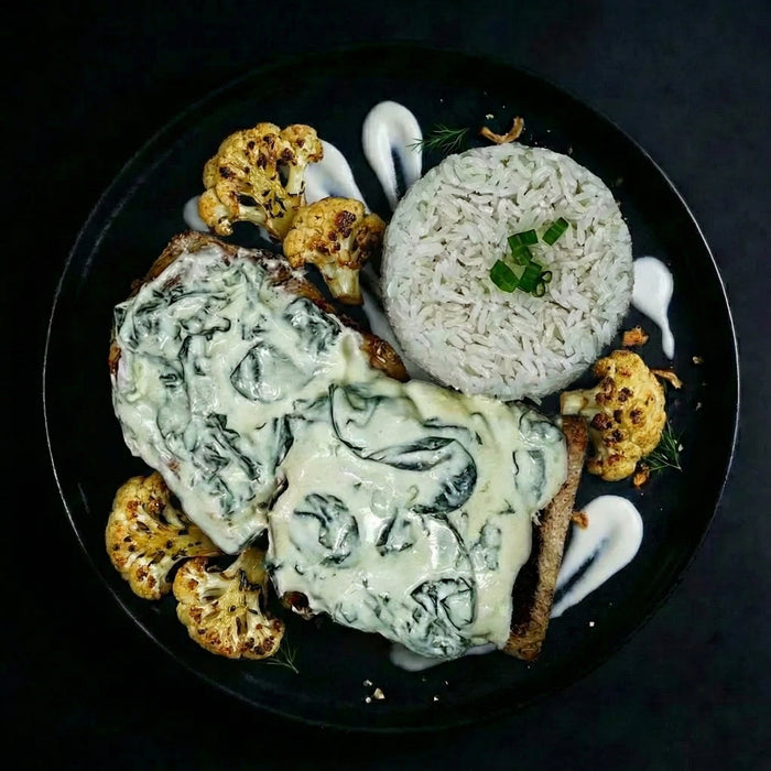 Plated dish with spinach artichoke dip, rice, and roasted cauliflower on a dark background