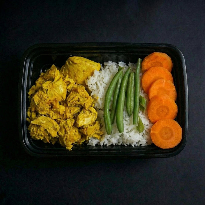 Plated meal with yellow scrambled eggs, white rice, green beans, and orange carrot slices on a black background.