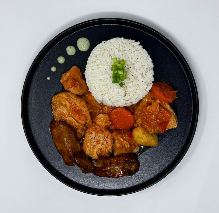 Plated dish with rice, chicken, carrots, and vegetables on a white background