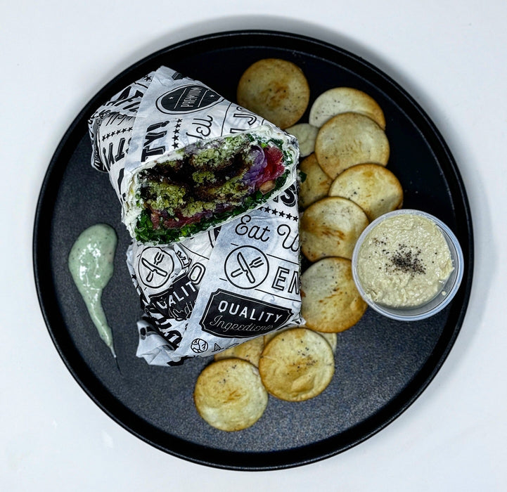 Burrito on a black plate with chips and dip, branded wrap