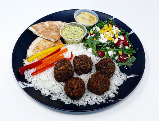 Plated meal with falafel, rice, vegetables, and salad on a white background