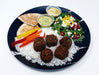 Plated meal with falafel, rice, vegetables, and salad on a white background