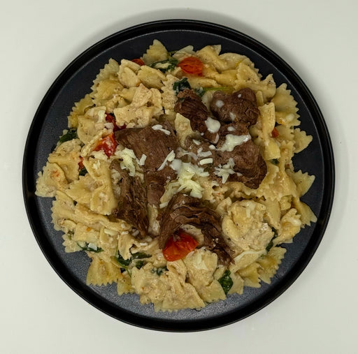Pasta dish with meat and vegetables on a black plate