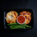 Plated dish with stuffed zucchini boats, green beans, and a side of red sauce on a black background
