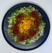 Plated dish with ground meat, lettuce, cheese, and salsa on a white background