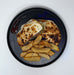 Plated dish with grilled bread and potato wedges on a white background