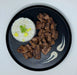 Black plate with rice and guava teriyaki chicken chunks on a light gray background