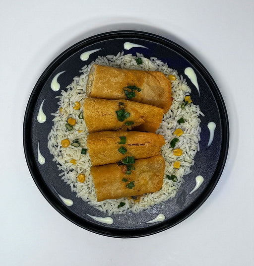 Rolls on a bed of rice with garnishes on a black plate