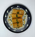 Rolls on a bed of rice with garnishes on a black plate