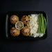 Plated meal with meatballs, rice, and green beans on a dark background