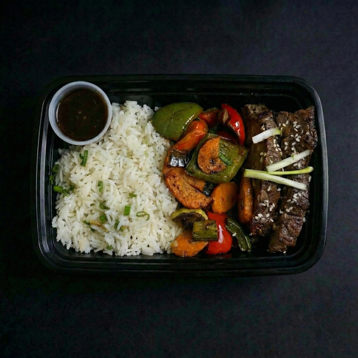 Plated meal with rice, vegetables, and meat on a dark background