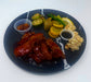 Plated dish with chicken wings, vegetables, and sauces on a dark plate. Made by Spartan Meal Preps, a NJ Meal Prep Delivery Company. 