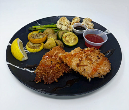 Plated dish with fried chicken, vegetables, and sauces on a black plate.