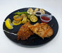 Plated dish with fried chicken, vegetables, and sauces on a black plate.