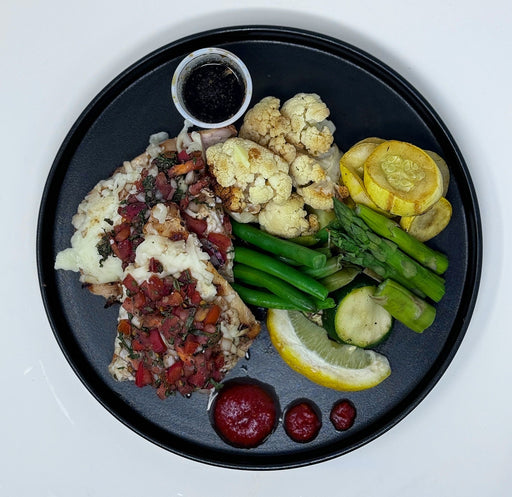Plated dish with cauliflower, zucchini, green beans, and a side of rice with meat on a black plate.