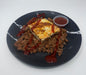Plated dish with ground meat, omelette, and red sauce on a black plate.