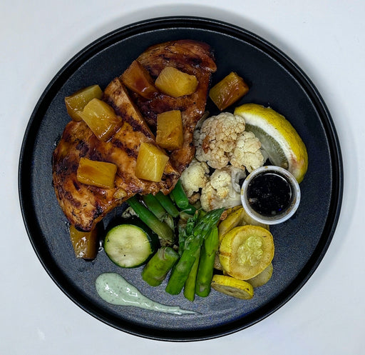 Plated dish with grilled meat, vegetables, and sauces on a black plate. a meal made by spartan meal preps.