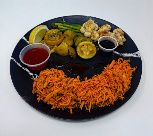 Plated dish with shredded orange food, vegetables, and sauces on a black plate.