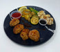 Plated meal with meatballs, vegetables, and sauces on a black plate.