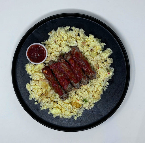 Plate with scrambled eggs, sausages, and ketchup on a white background made by spartan meal preps a new jersey meal prep company