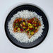 Heart-shaped grilled chicken with pineapple salsa on a bed of rice on a black plate.