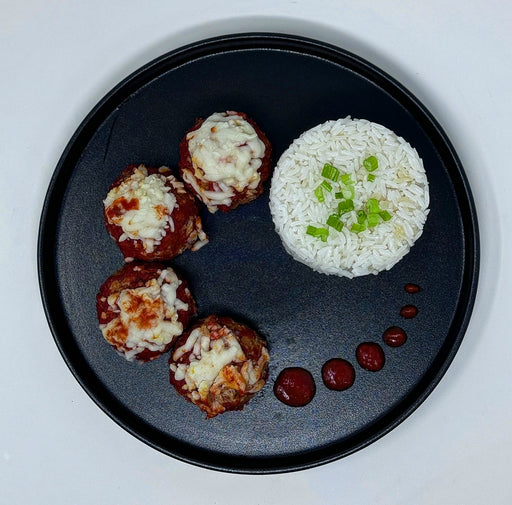 Black plate with meatballs and a side of rice on a white background