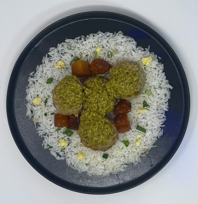 Plated dish with rice, green balls, and brown cubes on a white background